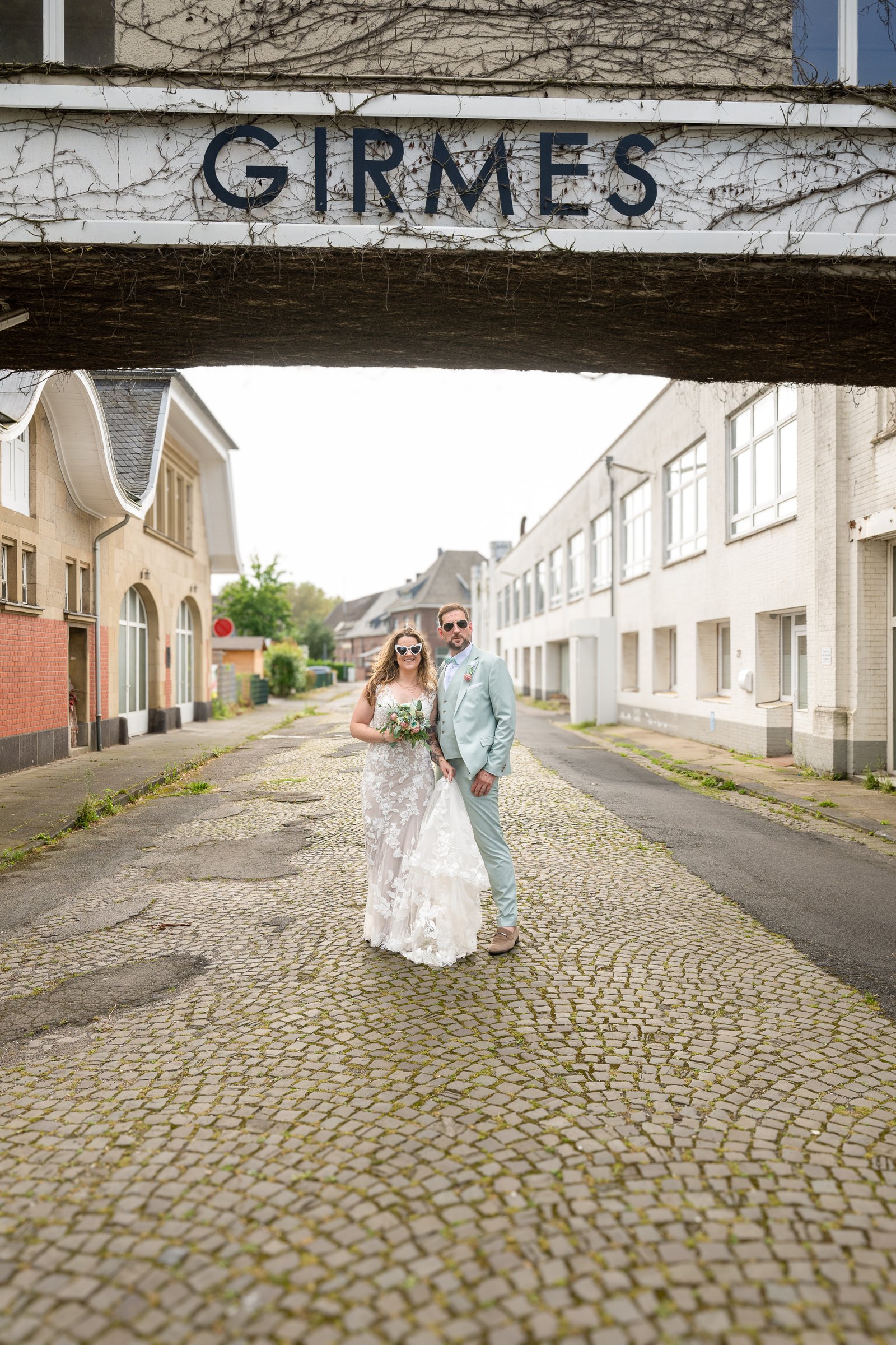 Lena und René als Brautpaar vor einer urbanen Industriearchitektur.