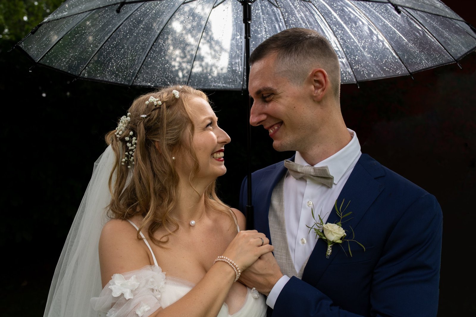 Carrie und Justin schauen sich unter einem regennassen Schirm an