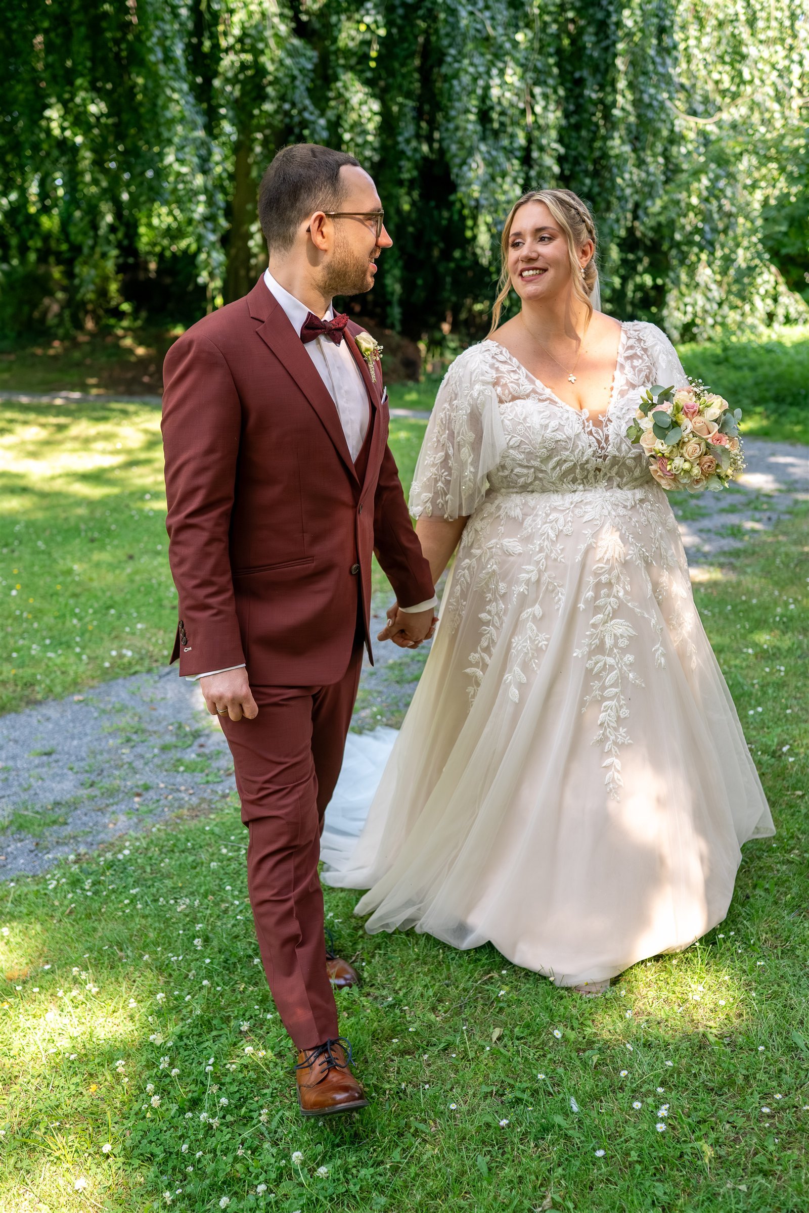 Jule und Marcel gehen Hand in Hand durch einen Park