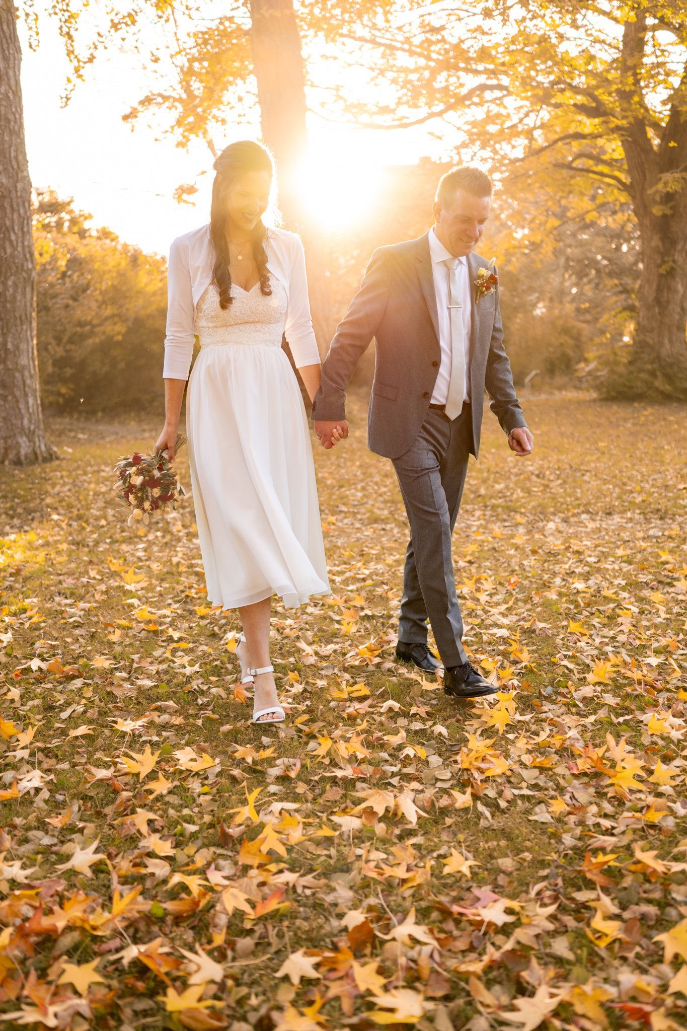 Laura und Enno gehen Hand in Hand durch goldenes Herbstlaub
