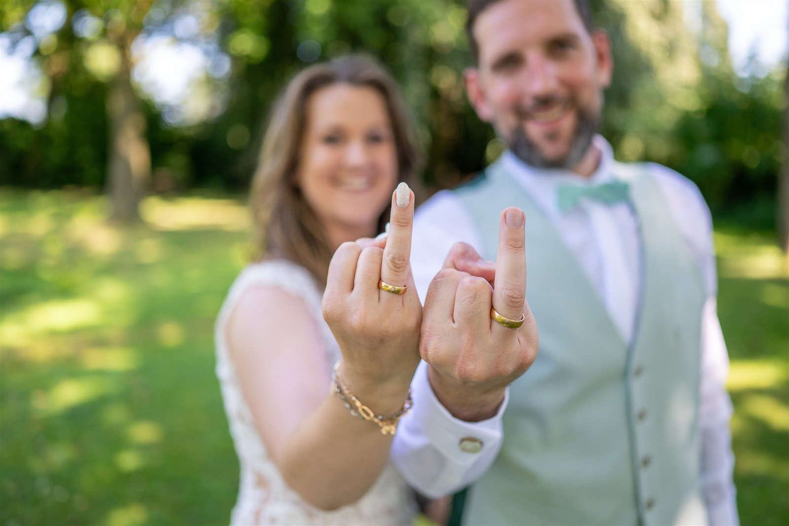 Lena und René zeigen lachend ihre Eheringe in die Kamera