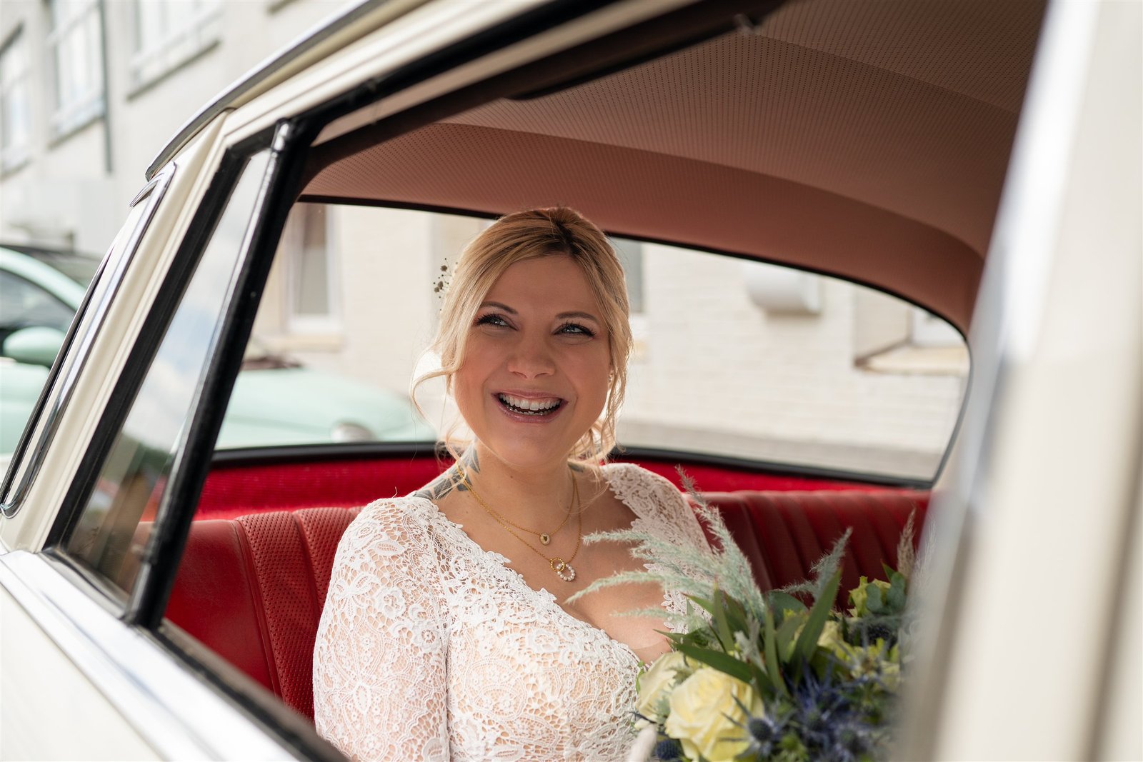 Sophie lächelt bei ihrer Ankunft aus dem roten Oldtimer