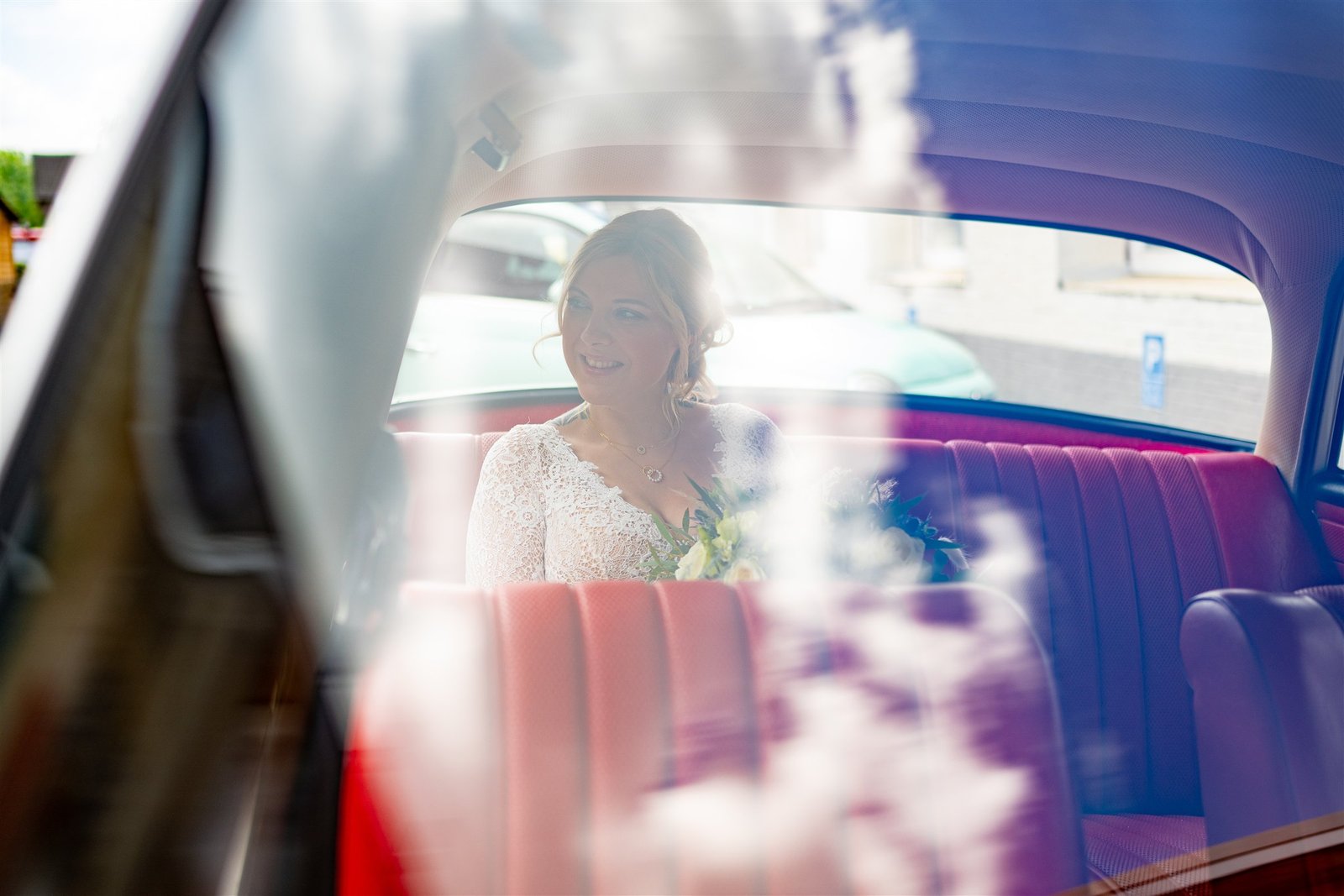 Sophie sitzt während ihrer Hochzeit im Oldtimer