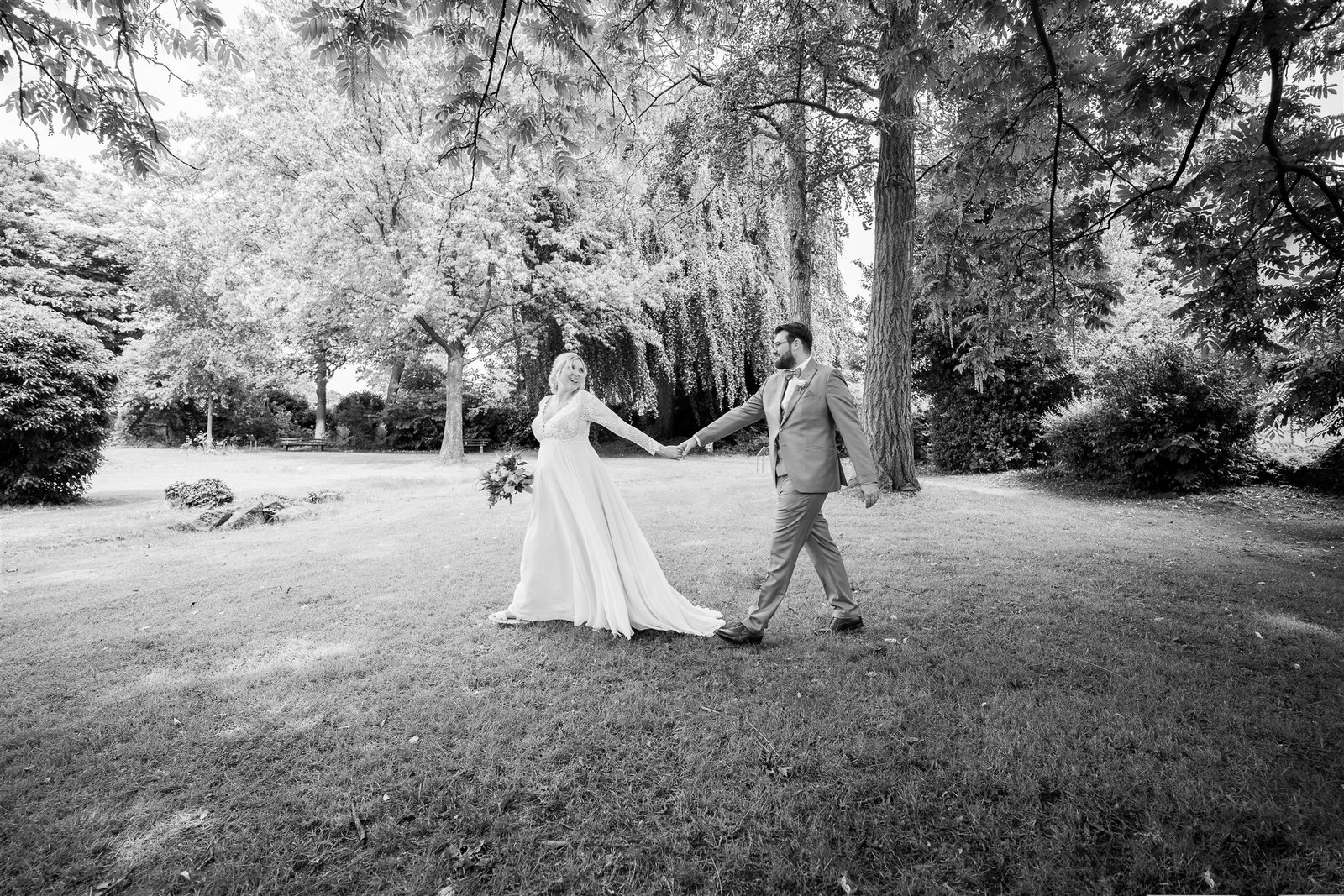 Sophie und Björn laufen Hand in Hand durch den Park in Schwarzweiß